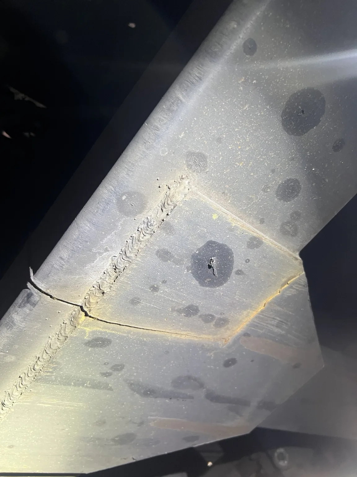 Cracked steel semi-trailer frame at an existing welded joint before repair in Gadsden, Alabama