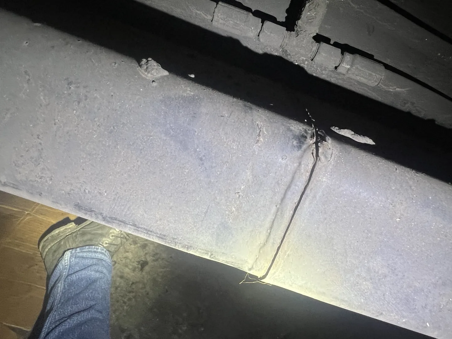 Open crack extending across the side of a steel semi-trailer frame member