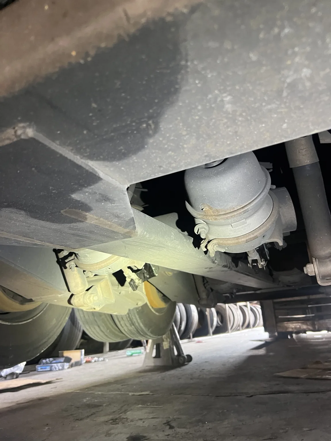 Wider view beneath the semi-trailer showing the frame and nearby axle assembly
