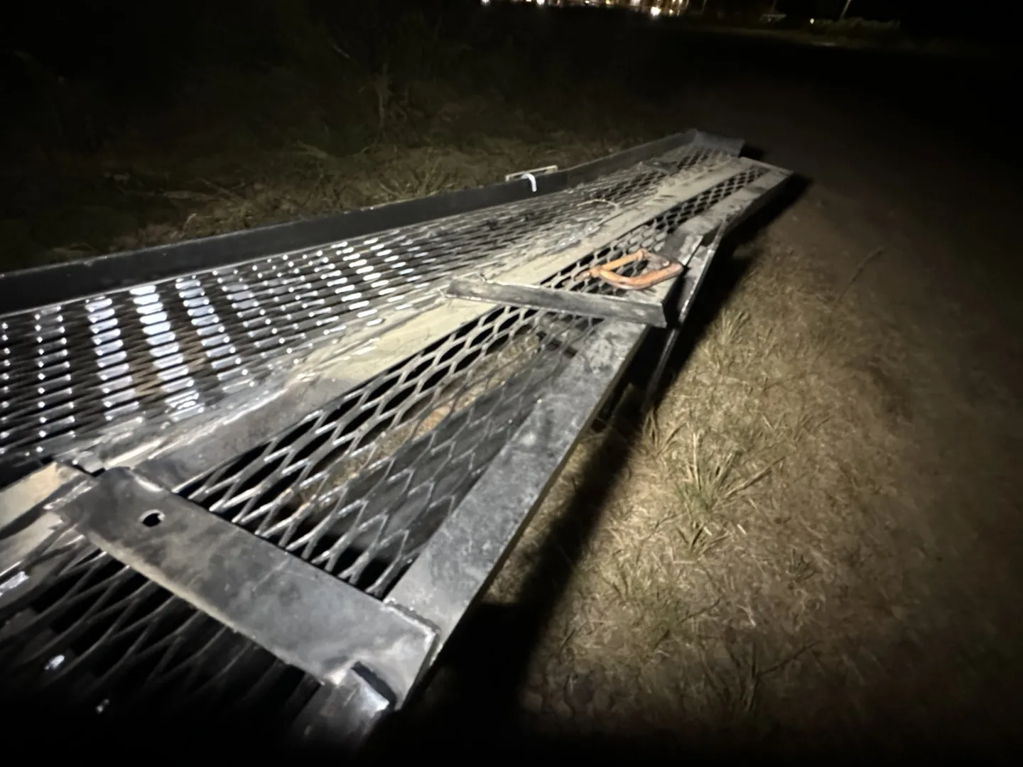 Billboard steel frame and expanded-metal sections at the Guntersville work site after dark