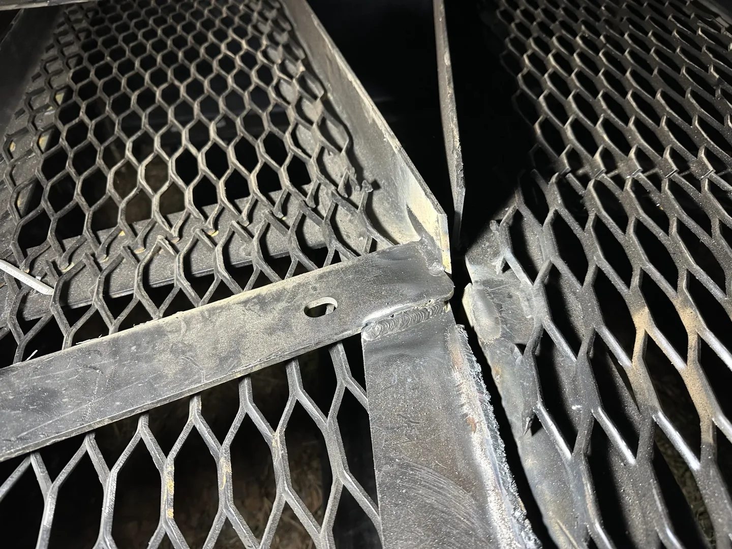 Slotted steel mounting plate and welds beside the billboard's expanded-metal sections